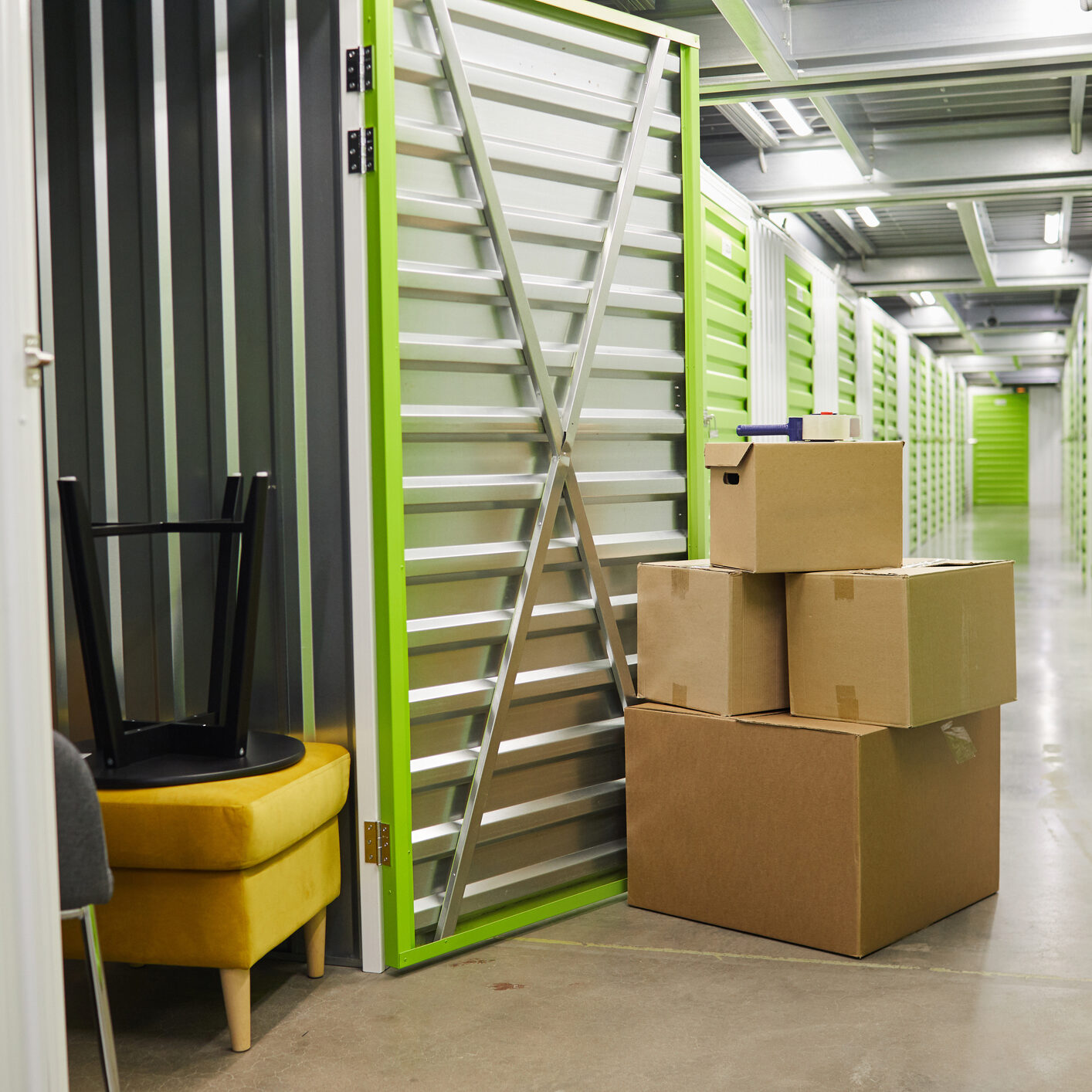 Background image of cardboard boxes stacked by open door of self storage unit, copy space